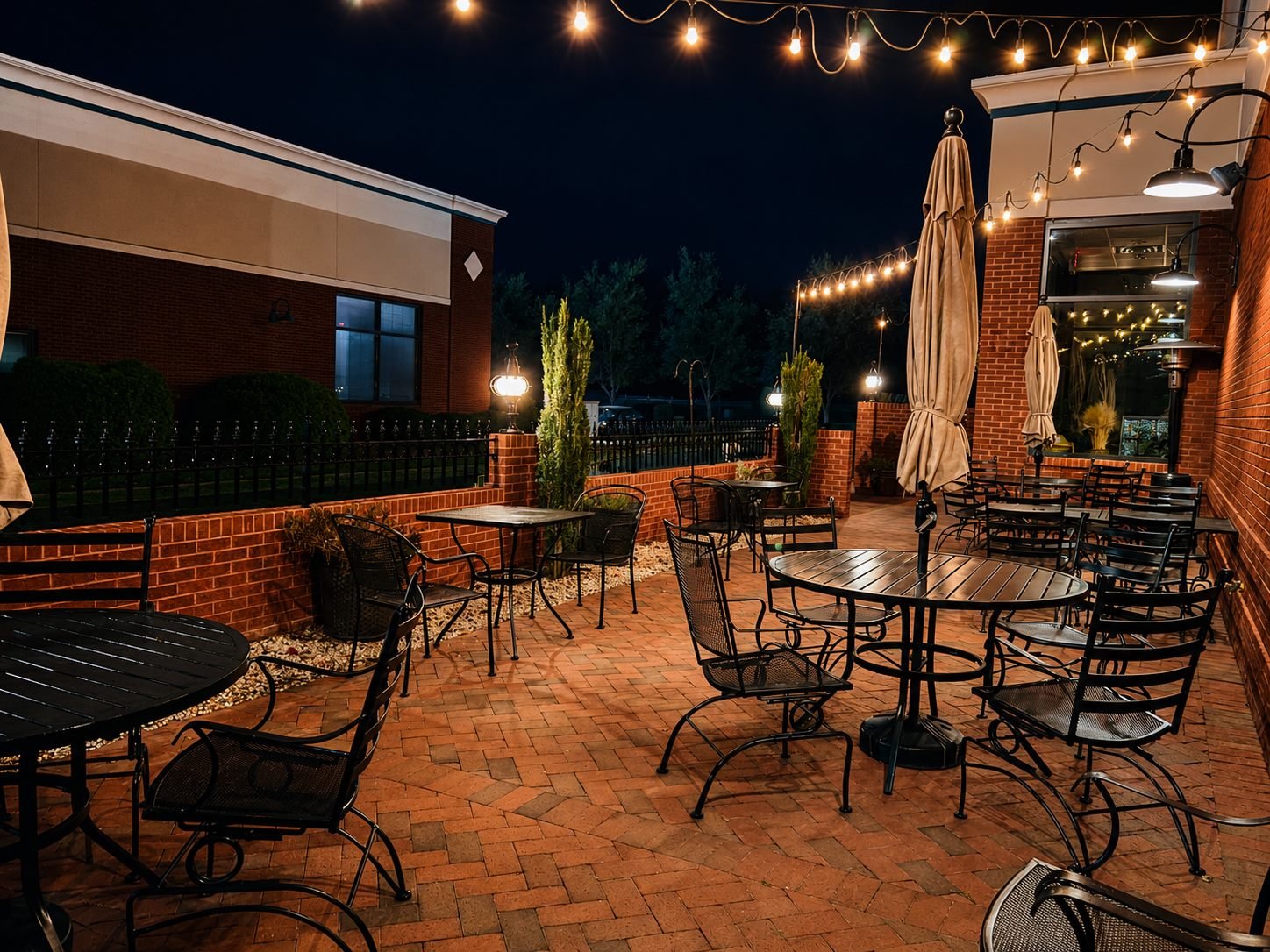 Skylines' string-lit brick patio at night with wrought-iron tables